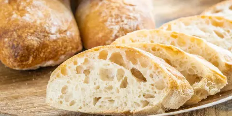 Frisch gebackene Ciabatta-Brote, aufgeschnitten auf einem Holzbrett. Dieses Ciabatta Rezept ergibt luftiges Brot mit knuspriger Kruste.