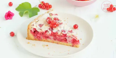 Ein Stück von Omas Johannisbeerkuchen mit Baiser, garniert mit frischen roten Johannisbeeren und Puderzucker.