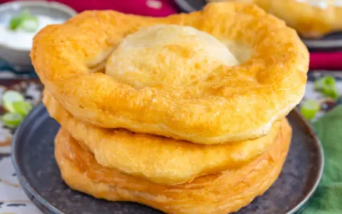 Goldbraune, fluffige Langos stapeln sich auf einem Teller. Ein köstliches Langos Rezept für zu Hause.