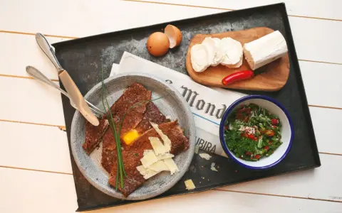 Herzhafte Galette Bretonne mit Ei, Käse und Salat, dazu Ziegenkäse und Chili.
