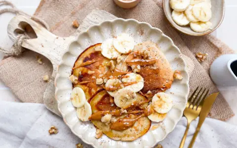 Leckere bananen pancakes ohne ei, garniert mit Bananenscheiben, Nüssen und einer cremigen Sauce. Ein Genuss für jeden Morgen!