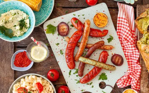 Würstchen, Maiskolben, Nudelsalat und Kräuterbutter – alles für ein perfektes Grill-Beilagen-Festmahl.