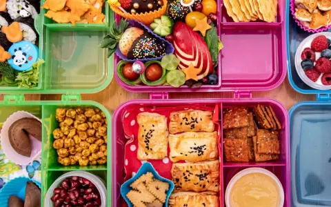 Bunte Bento-Boxen mit Sushi, Obst, Keksen und Gebäck. Perfekt für to go rezepte und kleine Entdecker.