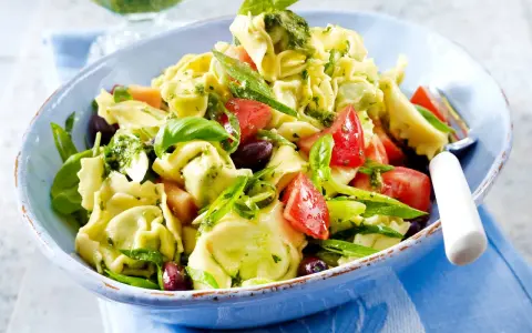 Ein bunter Tortellinisalat mit frischen Tomaten, Oliven, Basilikum und einem leckeren Pesto.
