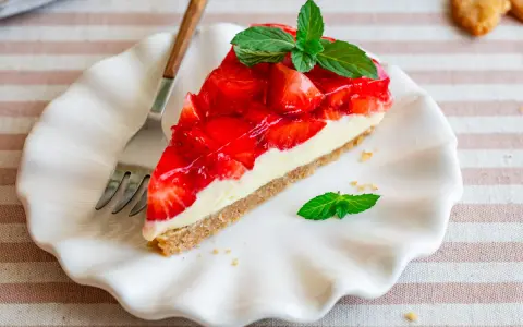 Ein Stück Erdbeerkuchen mit einer cremigen Füllung und glänzender Erdbeerschicht, garniert mit Minze. Diese torte ohne sahne ist ein Genuss.