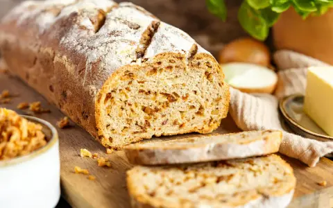 Frisch gebackenes Zwiebelbrot mit knusprigen Röstzwiebeln, bereit für ein köstliches Zwiebelbrot Rezept. Daneben Butter und frische Kräuter.