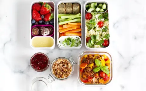 Vorbereitete Mahlzeiten für das meal prep einfrieren: Obst, Gemüse-Sticks, Hummus, Couscous-Salat und Linseneintopf.