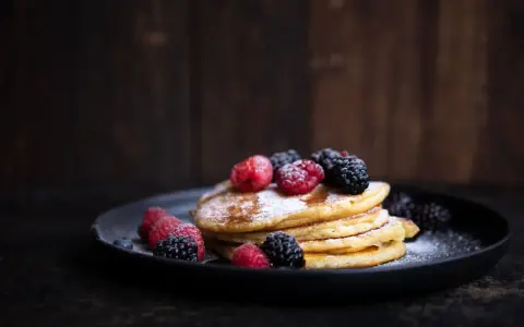 Ein Stapel fluffiger Pancakes, garniert mit frischen Beeren und Puderzucker. Ein perfektes pancakes rezept fluffig für jeden Anlass.