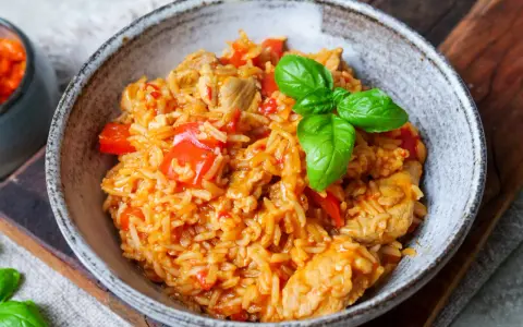 Herzhaftes serbisches Reisfleisch mit Paprika und Basilikum in einer rustikalen Schüssel, bereit zum Genießen.