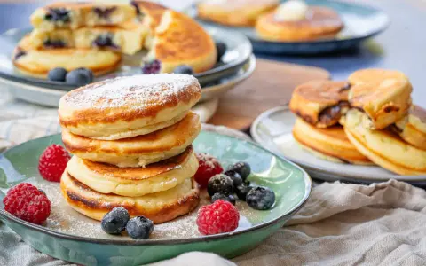 Fluffige Buttermilch Pancakes, mit Puderzucker bestäubt und garniert mit frischen Beeren. Ein Genuss für jeden Morgen!