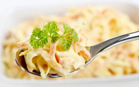 Ein Löffel cremiger Krautsalat, garniert mit Petersilie. Perfekt für jedes coleslaw rezept.