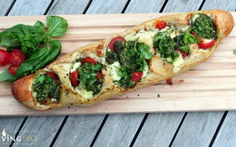 Ein knuspriges Baguette mit Pesto, geschmolzenem Käse und saftigen Tomaten, garniert mit frischem Basilikum.