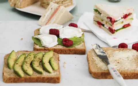 Schnelles Essen ohne Kochen: Mehrere belegte Brote mit Avocado, Ziegenkäse und Himbeeren, bereit zum Genuss.