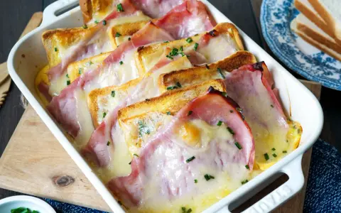 Herzhafte Toast-Rezepte: Geröstetes Brot mit Schinken und geschmolzenem Käse, bestreut mit Schnittlauch, in einer Auflaufform.
