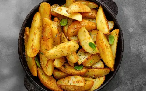 Goldbraune Ofenkartoffeln, gewürzt mit Kräutern, in einer schwarzen Pfanne. Perfekt für ein einfaches Ofenkartoffeln Rezept.