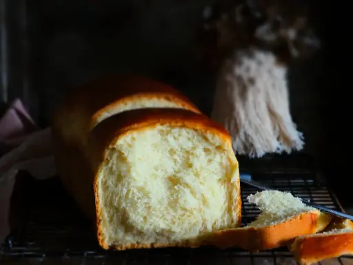 Ein frisch gebackenes Brioche-Brot, das auf einem Rost abkühlt. Die goldbraune Kruste und die weiche, helle Krume lassen das brioche rezept gelingen.