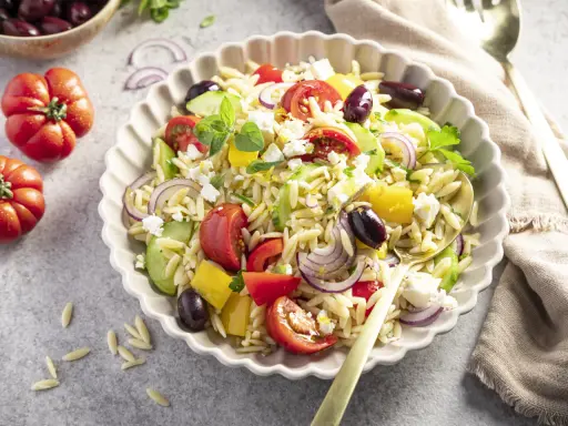 Ein bunter, schneller Kritharaki-Salat mit Tomaten, Gurken, Paprika, roten Zwiebeln, Oliven und Feta.