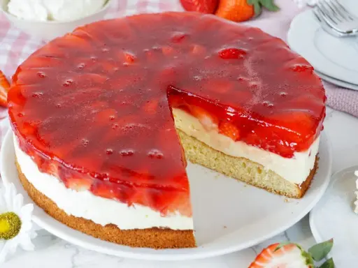 Ein saftiger erdbeerkuchen mit vanillepudding und einer glänzenden Erdbeer-Gelee-Schicht. Ein Stück ist bereits herausgeschnitten.