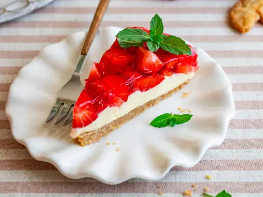 Ein Stück Erdbeerkuchen mit einer cremigen Füllung und glänzender Erdbeerschicht, garniert mit Minze. Diese torte ohne sahne ist ein Genuss.