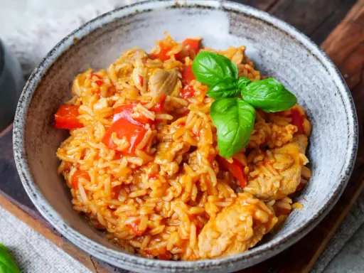 Herzhaftes serbisches Reisfleisch mit Paprika und Basilikum in einer rustikalen Schüssel, bereit zum Genießen.
