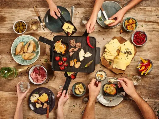 Raclette-Abend: Käse schmilzt, Fleisch brät, dazu Brot, Oliven, Paprika und Pilze – so vielfältig, was man zu Raclette essen kann!