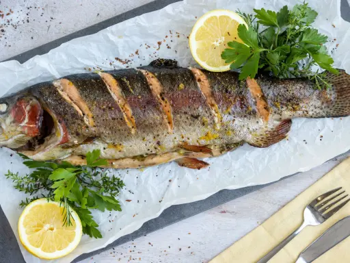 Saftige Lachsforelle im Backofen, garniert mit Zitrone und frischen Kräutern. Ein Genuss für Gaumen und Augen.