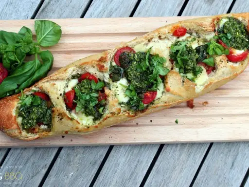Ein knuspriges Baguette mit Pesto, geschmolzenem Käse und saftigen Tomaten, garniert mit frischem Basilikum.