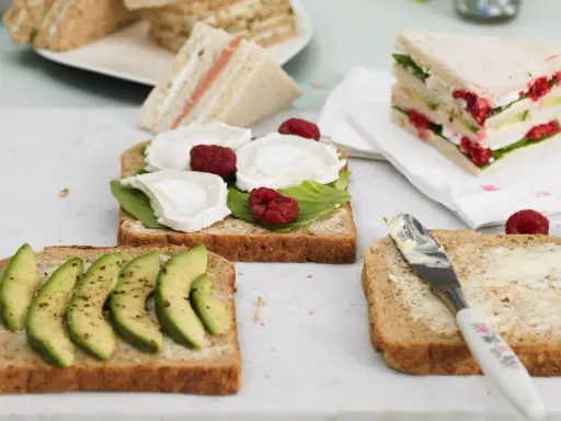 Schnelles Essen ohne Kochen: Mehrere belegte Brote mit Avocado, Ziegenkäse und Himbeeren, bereit zum Genuss.