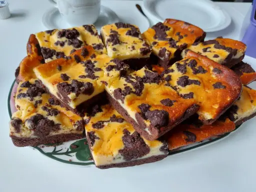 Ein Blech russischer Zupfkuchen, in Stücke geschnitten, mit Schokoladenstreuseln und cremiger Füllung.