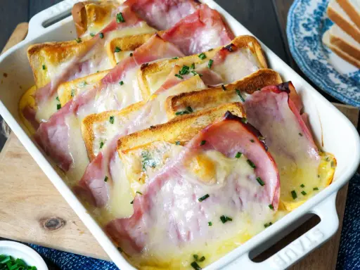 Herzhafte Toast-Rezepte: Geröstetes Brot mit Schinken und geschmolzenem Käse, bestreut mit Schnittlauch, in einer Auflaufform.