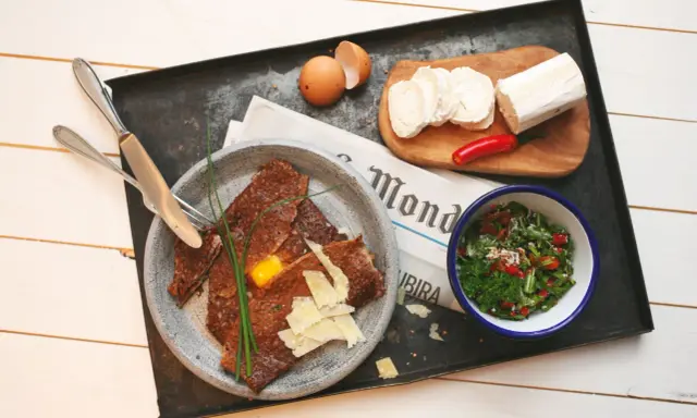 Herzhafte Galette Bretonne mit Ei, Käse und Salat, dazu Ziegenkäse und Chili.