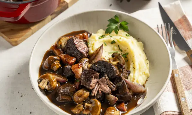 Boeuf Bourguignon mit cremigem Kartoffelpüree als Beilage, garniert mit Petersilie. Ein Festmahl!