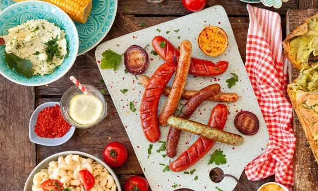 Würstchen, Maiskolben, Nudelsalat und Kräuterbutter – alles für ein perfektes Grill-Beilagen-Festmahl.