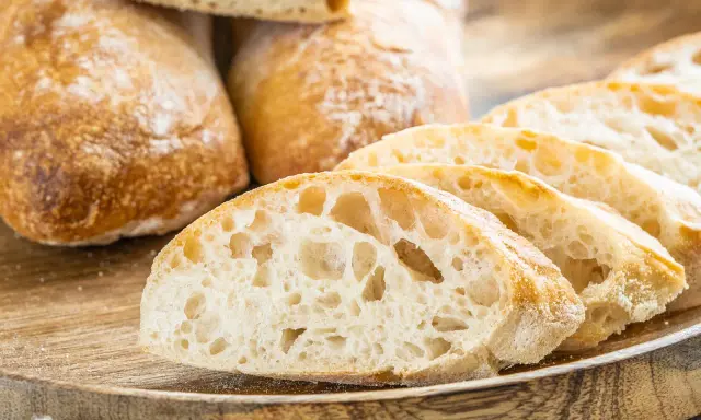 Frisch gebackene Ciabatta-Brote, aufgeschnitten auf einem Holzbrett. Dieses Ciabatta Rezept ergibt luftiges Brot mit knuspriger Kruste.