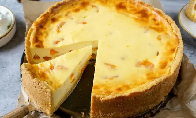 Ein saftiger Mandarinen Schmand Kuchen mit einem knusprigen Boden und cremiger Füllung, ein Stück wurde bereits herausgeschnitten.