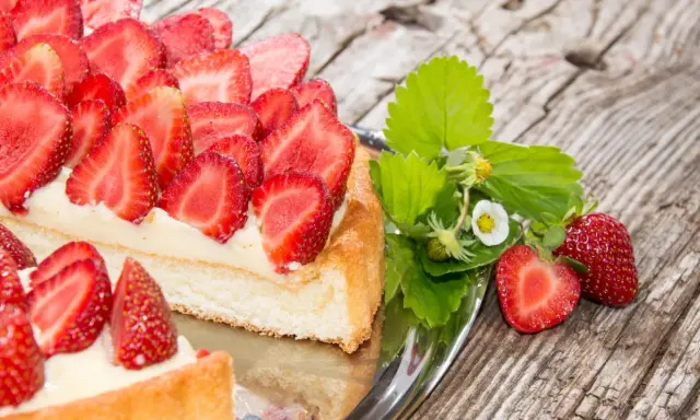 Ein köstlicher Erdbeerkuchen mit frischen Erdbeeren und Sahne auf einem Silbertablett. Perfekt für ein Erdbeerkuchen Rezept.