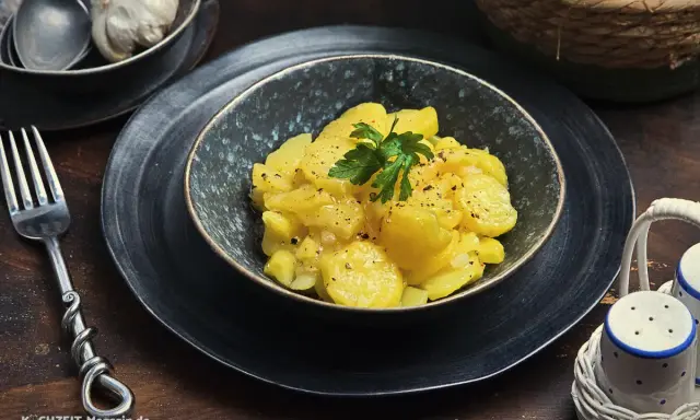 Ein köstlicher Kartoffelsalat, perfekt für jedes Kartoffelsalat Rezept. Mit frischer Petersilie garniert, wartet er darauf, genossen zu werden.