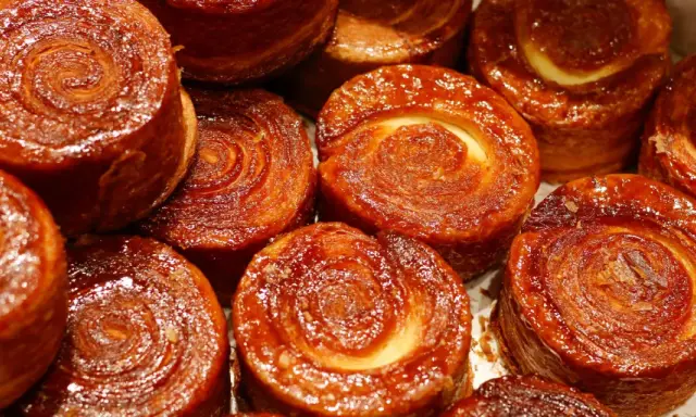 Nahaufnahme von karamellisierten Kouign Amann Gebäckstücken mit spiralförmiger Teigstruktur.