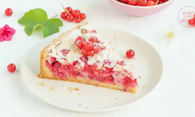 Ein Stück von Omas Johannisbeerkuchen mit Baiser, garniert mit frischen roten Johannisbeeren und Puderzucker.