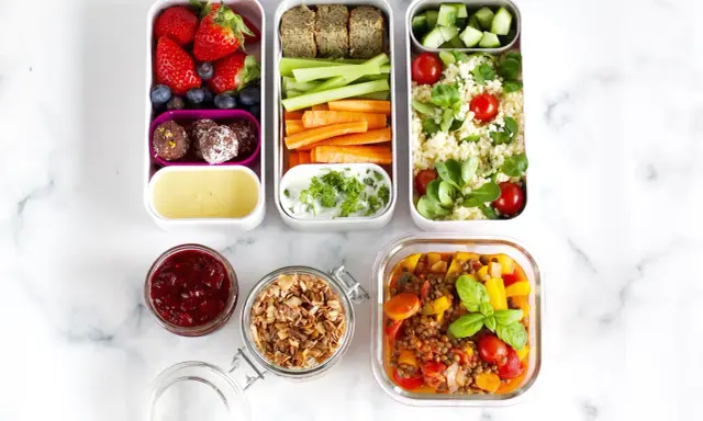 Vorbereitete Mahlzeiten für das meal prep einfrieren: Obst, Gemüse-Sticks, Hummus, Couscous-Salat und Linseneintopf.