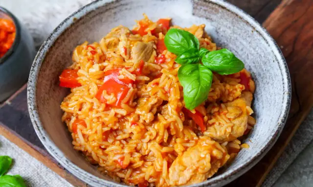 Herzhaftes serbisches Reisfleisch mit Paprika und Basilikum in einer rustikalen Schüssel, bereit zum Genießen.
