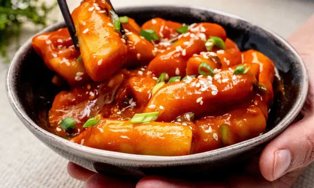 Tteokbokki in einer Schüssel, garniert mit Frühlingszwiebeln und Sesam. Diese tollen Rezepte sind ein Genuss!
