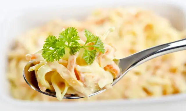 Ein Löffel cremiger Krautsalat, garniert mit Petersilie. Perfekt für jedes coleslaw rezept.