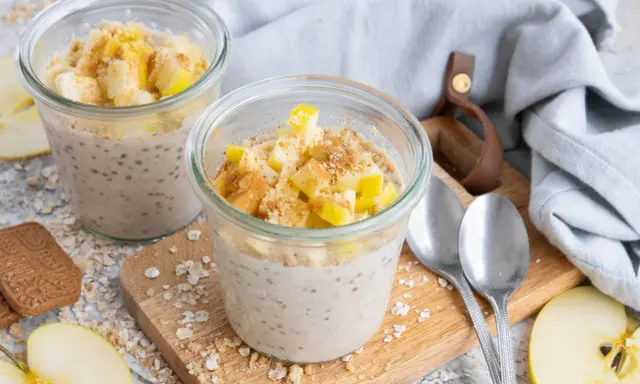 Zwei Gläser mit Overnight Oats Grundrezept, garniert mit Apfelstücken und Zimt. Perfekt für ein schnelles Frühstück.