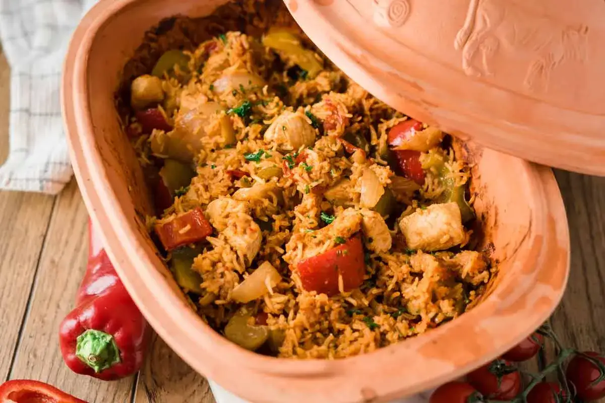 Serbisches Reisfleisch mit Paprika und Huhn, serviert in einem Tontopf.
