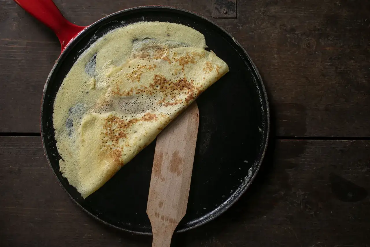 Ein goldbrauner Cr&ecirc;pe liegt gefaltet in einer Pfanne. Das cr&ecirc;pes teig rezept original ist einfach und gelingt mit diesem Ergebnis.