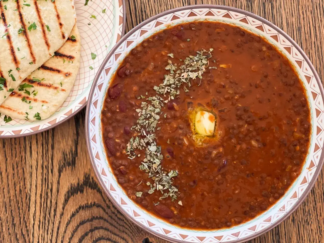 Herzhaftes Dal Makhani mit Butter und Kr&auml;utern, serviert mit gegrilltem Naan.