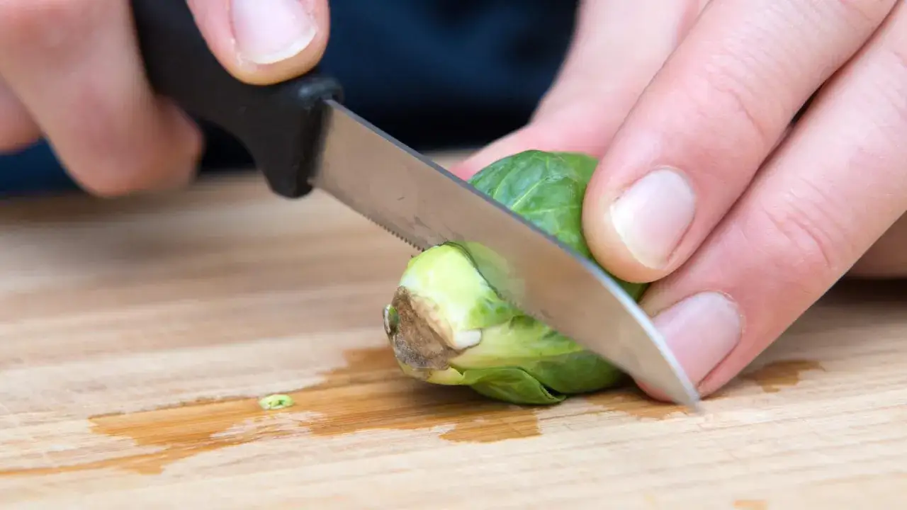 H&auml;nde schneiden Rosenkohl auf einem Holzbrett zu, wie Oma es fr&uuml;her gemacht hat.