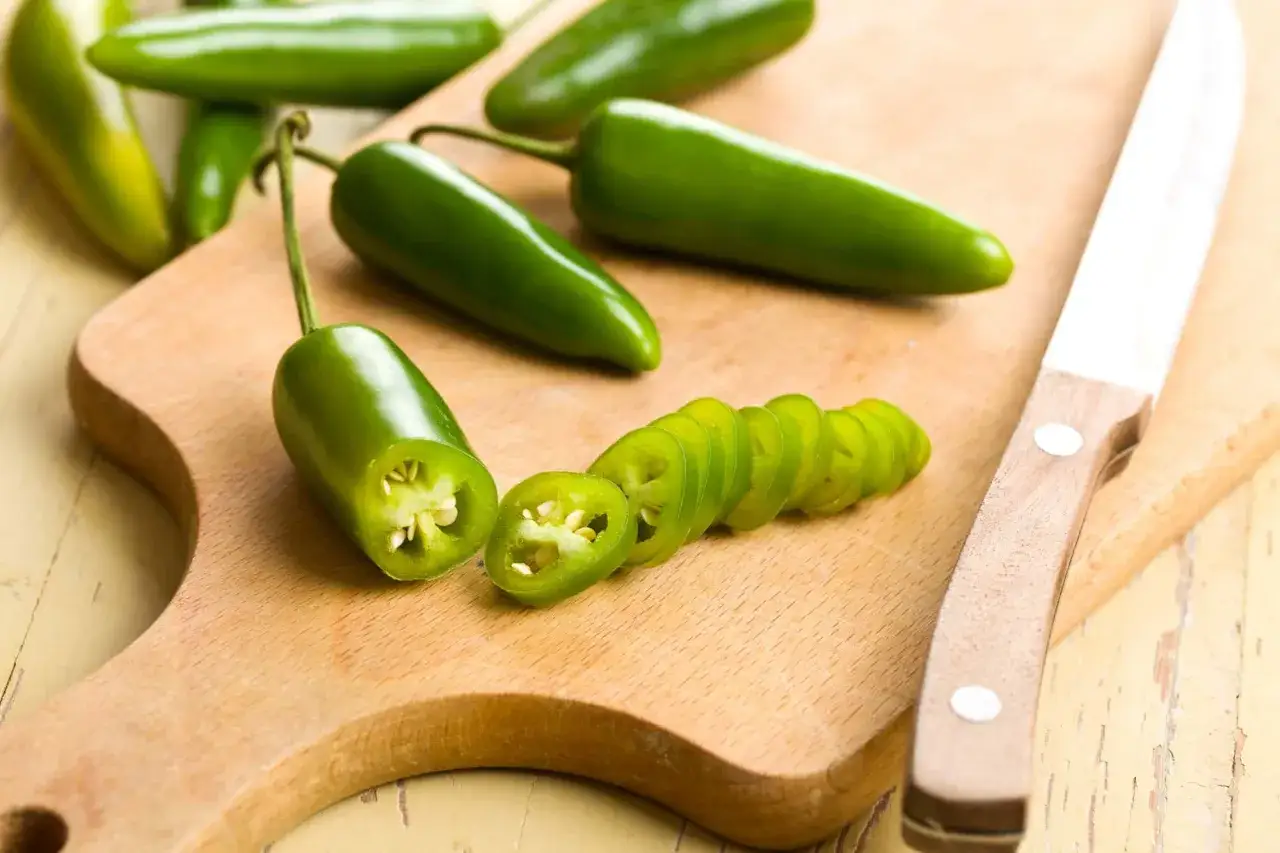 Gr&uuml;ne Jalape&ntilde;os werden auf einem Holzbrett geschnitten. Sie sind scharf und w&uuml;rzig, was sind Jalape&ntilde;os?