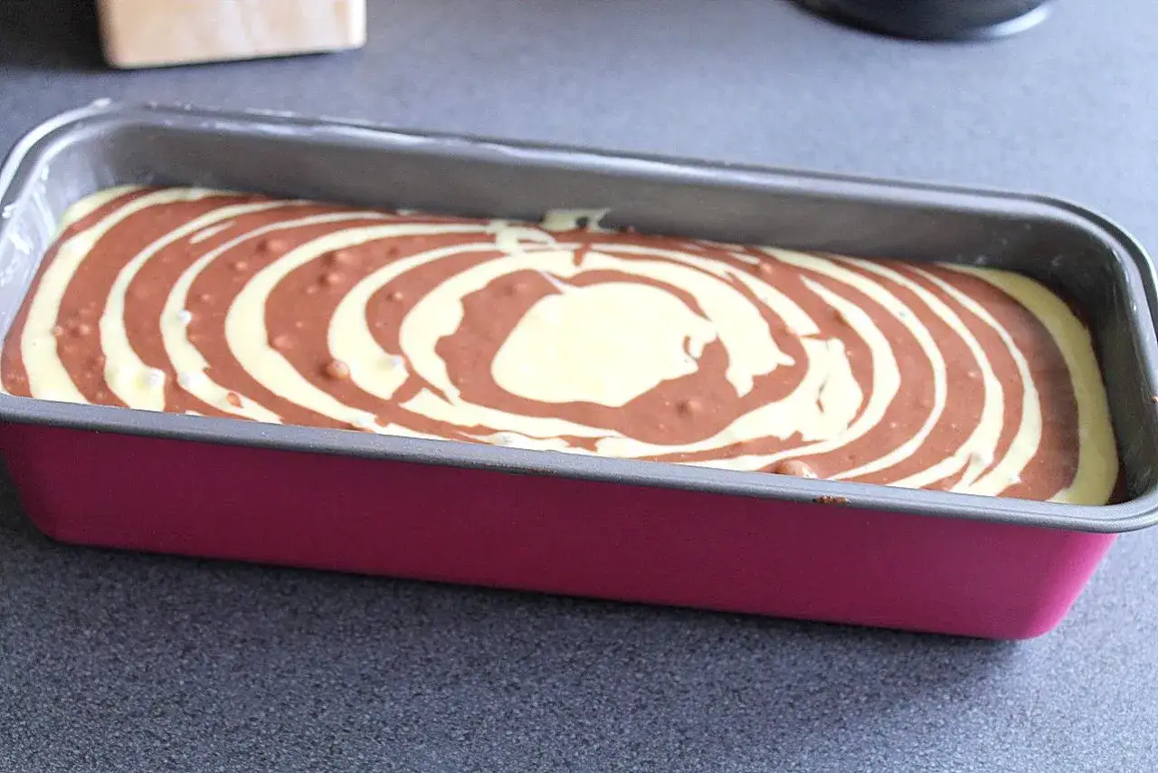 Zebrakuchen rezept: Teig mit Marmormuster in einer pinken Kastenform, bereit zum Backen.